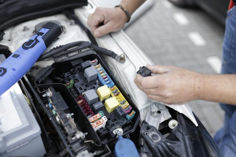 Car mechanic working on a cars electronics. — illustrative photo for electric car maintenance electronics